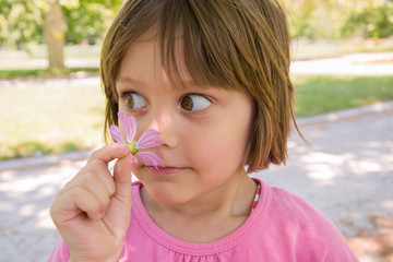 Happy little girl smelling flower