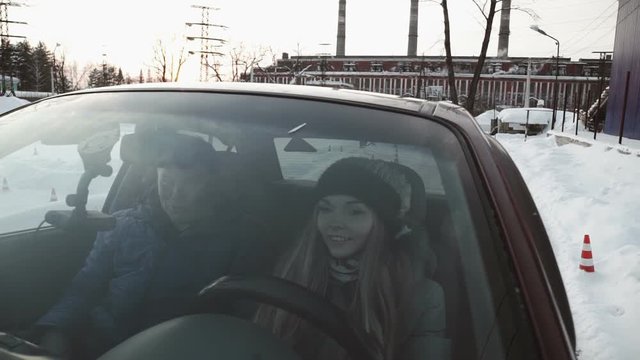 Driving instructor points out mirrors to pretty teenage girl sitting in car
