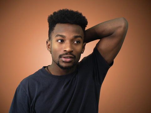 young man arm behind head orange studio background