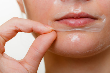 Woman removing facial peel off mask closeup