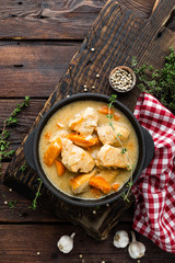 Meat stewed with carrots in sauce and spices in cast iron pan on dark wooden rustic background top view flat lay