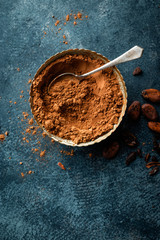 Cocoa powder and cacao beans on dark background, top view