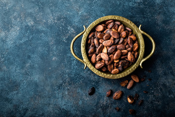 Cocoa beans on dark background, top view, copy space, flat lay