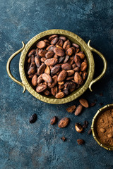 Cocoa beans and powder on dark background, top view, copy space, flat lay