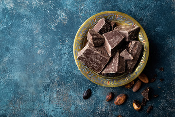 Dark chocolate pieces crushed and cocoa beans, culinary background, top view