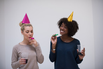 smiling women in party caps blowing to whistles