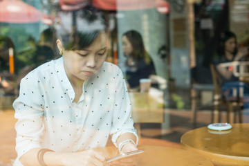 Fototapeta premium SOHO lifestyle Asian woman using smart phone for working and chatting in Cafe
