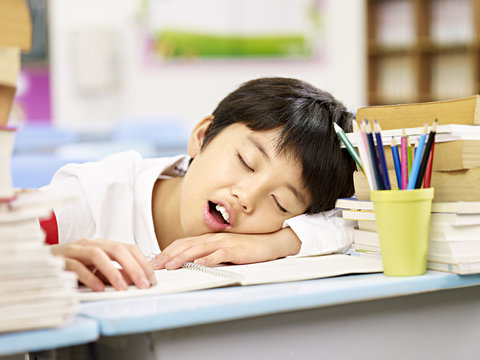 exhausted asian school boy falling asleep in classroom