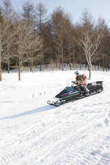 Fototapeta na wymiar Mother and child riding on snowmobile 