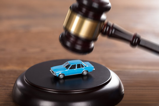 Gavel Striking On A Car Model