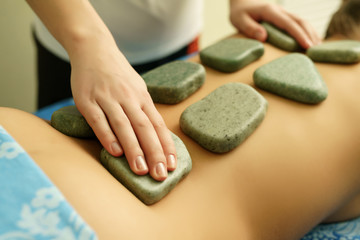 Stone massage in spa, focus on therapist hand