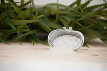 Natural bath salt, organic products on leaves background.