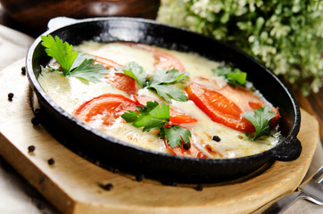 Beef tongue baked with potatoes in creamy sauce with cheese and tomatoes