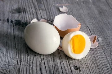 Abwaschbare Fototapete Sliced hard boiled eggs on wooden cutting board © mbruxelle