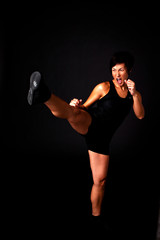 Woman kick boxing isolated on black.