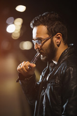 Vaping man holding a mod. A cloud of vapor. Stylish hipster with vape.