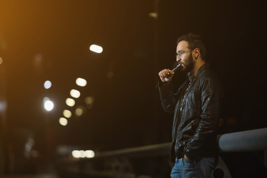 Vaping man holding a mod. A cloud of vapor. Stylish hipster with vape.