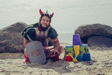 Dragon Costumed Man sits on the Beach as Knight of the Sand Castle