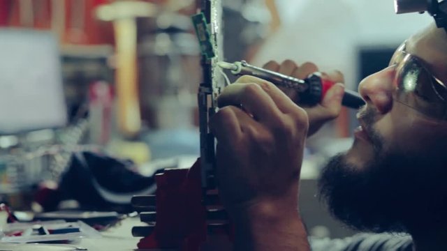 Man Soldering Circuit Board for Device at Engineering Workshop Table 