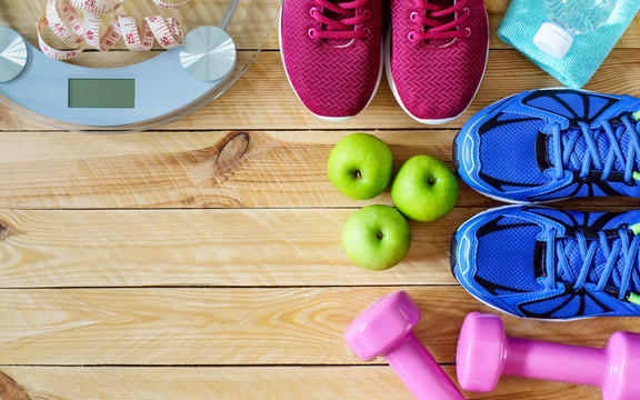 Fitness and weight loss concept, running shoes, dumbbells, tape measure, apples, bananas, weighting scale, top view with copy space