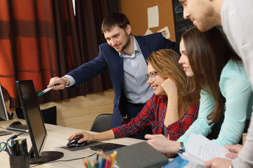 Group of young colleagues or busing laptop at office