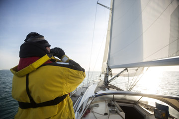 Man Looking Through Binoculars While On Sail Boat