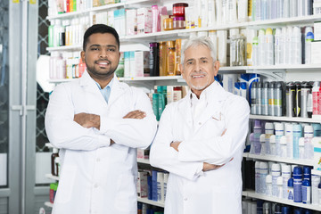Multiethnic Pharmacist Standing Arms Crossed In Pharmacy