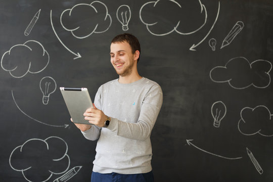 Young man with tablet by the wall
