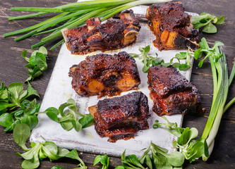 Barbecued spare ribs with fresh herbs on  wooden board.
