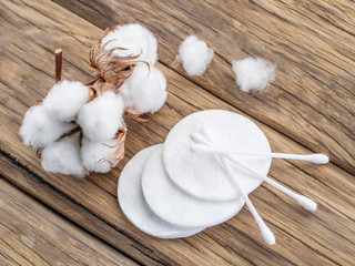 Fluffy cotton ball and cotton swabs and pads on wooden table.