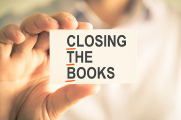 Businessman holding card with CTB CLOSING THE BOOKS acronym text