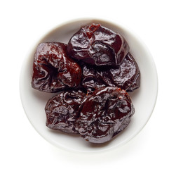 Bowl of prunes isolated on white, from above