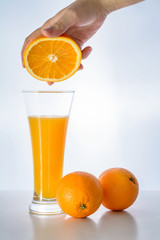  Glass of fresh orange juice and woman hand holding orange fruit