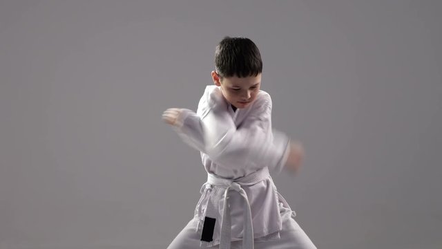 A very young karateka demostrates a self defence block and a strike in studio