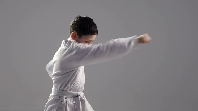 A young karateka does straitforward strikes, dressed in a white kimono