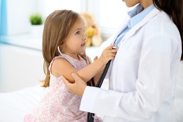 Obraz premium Happy little girl at health exam at doctor office. Medicine and health care concept