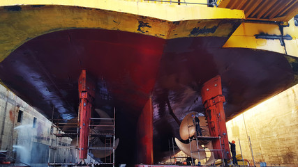 men at work at shypyard under ship hull