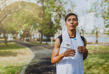 Sports man drinking water after exercising on background public park , healthy lifestyle.