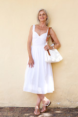 happy older woman in spring dress standing with purse