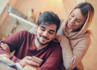 Loving couple sitting in the cafe, having fun with mobile phone