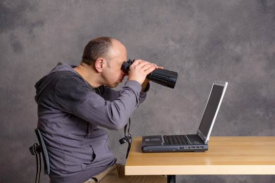 young  man looking with binoculars at the screen