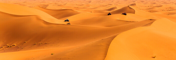 Tourists driving quads and all-terrain vehicles in sahara dunes - obrazy, fototapety, plakaty