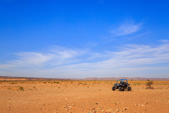 Merzouga, Morocco - Feb 26, 2016: Side view on blue Polaris RZR 800 with it's pilots in Morocco desert near Merzouga. Merzouga is famous for its dunes, the highest in Morocco.