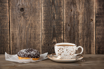 Chocolate donut and coffee cup on wooden table