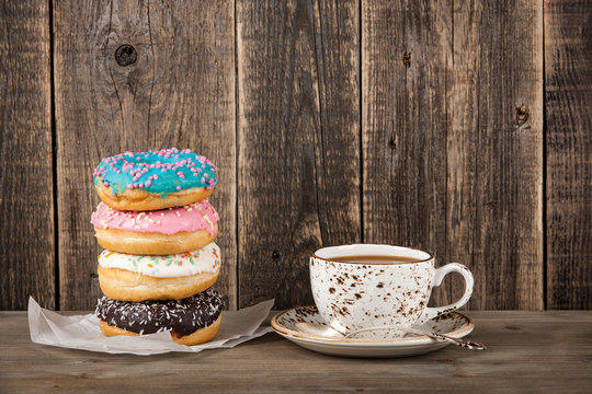 Colorful donuts and coffee cup on wooden table