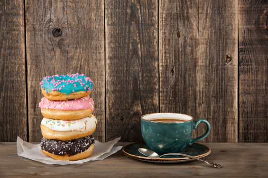 Colorful donuts and coffee cup on wooden table