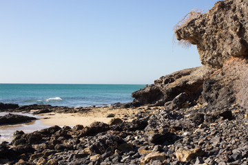 Black rocks of Costa Calma beach. Blue coastline. Playa Barca, Fuerteventura, Canary islands, Spain. Istmo de la pared view