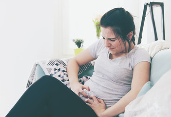 Young woman in pain while sitting on comfortable sofa, home