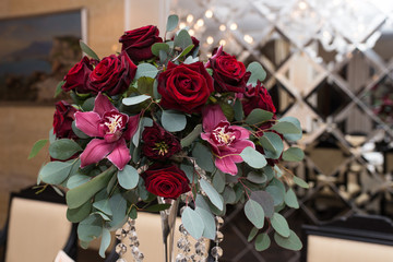 Wedding arrangement with fresh red roses, orchids and eucalyptus on the banquet table