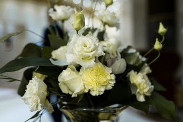 Wedding arrangement with fresh white roses, carnation, and greenery on the banquet table